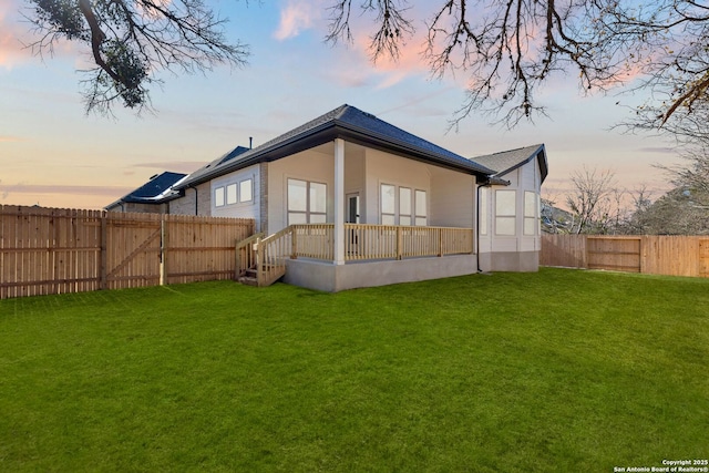 back house at dusk with a lawn