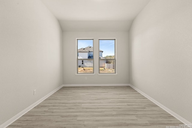 empty room featuring lofted ceiling and light hardwood / wood-style floors