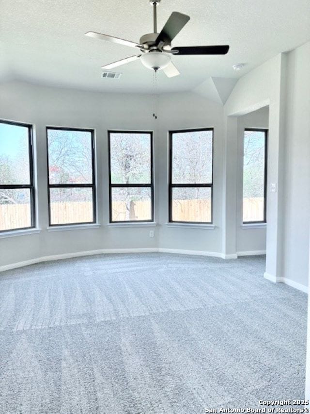 spare room featuring vaulted ceiling, carpet, a textured ceiling, and ceiling fan