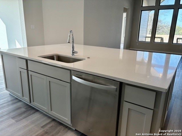 kitchen featuring sink, gray cabinets, dishwasher, and light wood-type flooring