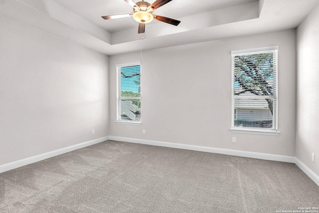 carpeted empty room featuring a raised ceiling and ceiling fan