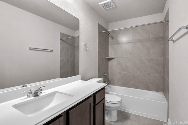 full bathroom with toilet, tile patterned floors, vanity, tiled shower / bath, and a textured ceiling