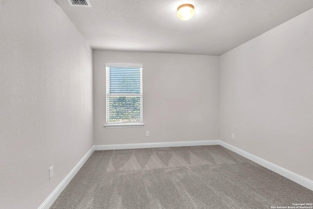 carpeted empty room featuring a textured ceiling