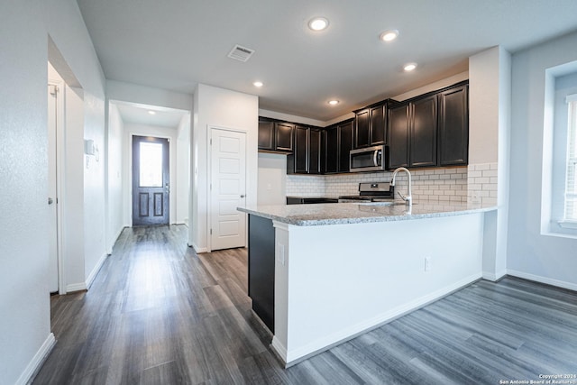 kitchen featuring kitchen peninsula, dark wood-type flooring, light stone countertops, and stainless steel appliances