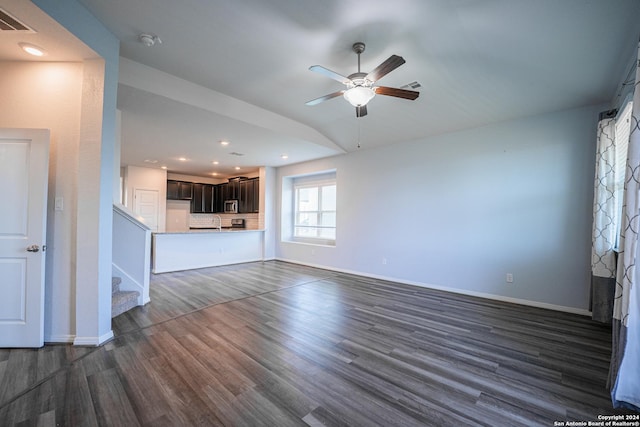 unfurnished living room with ceiling fan, vaulted ceiling, and dark wood-type flooring