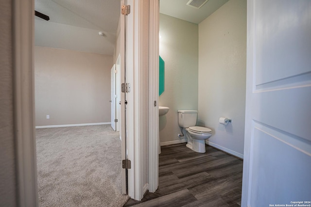 bathroom featuring wood-type flooring, toilet, and lofted ceiling