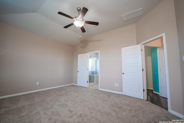 unfurnished bedroom featuring ensuite bath, carpet, vaulted ceiling, and ceiling fan