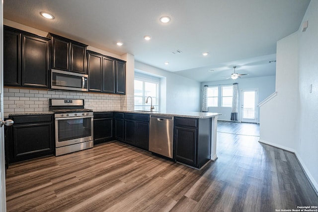 kitchen with tasteful backsplash, sink, kitchen peninsula, dark hardwood / wood-style flooring, and stainless steel appliances