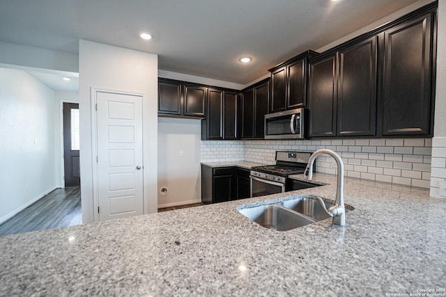 kitchen featuring sink, light stone counters, tasteful backsplash, and appliances with stainless steel finishes