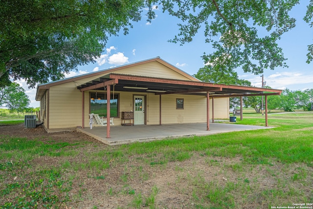 back of house with cooling unit, a lawn, and a patio area