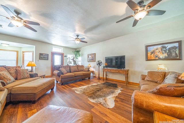 living room featuring dark hardwood / wood-style floors, ceiling fan, and a textured ceiling