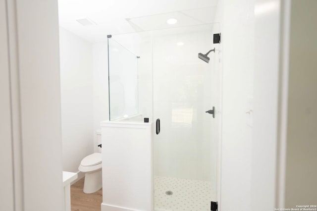 bathroom featuring hardwood / wood-style flooring, toilet, and an enclosed shower