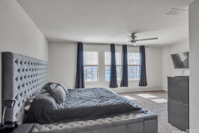 bedroom with carpet floors, a textured ceiling, and ceiling fan