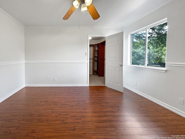 spare room featuring crown molding, dark wood-type flooring, and ceiling fan