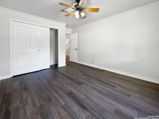 unfurnished bedroom featuring dark wood-type flooring, ceiling fan, ornamental molding, and a closet