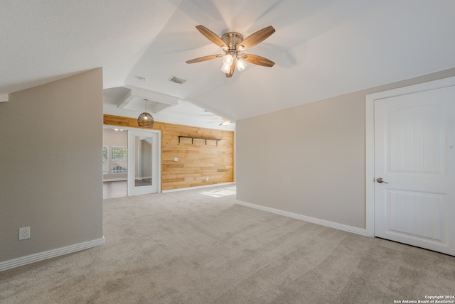 additional living space with wood walls, ceiling fan, lofted ceiling, and light colored carpet