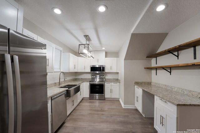 kitchen featuring light stone countertops, light hardwood / wood-style flooring, stainless steel appliances, and white cabinets