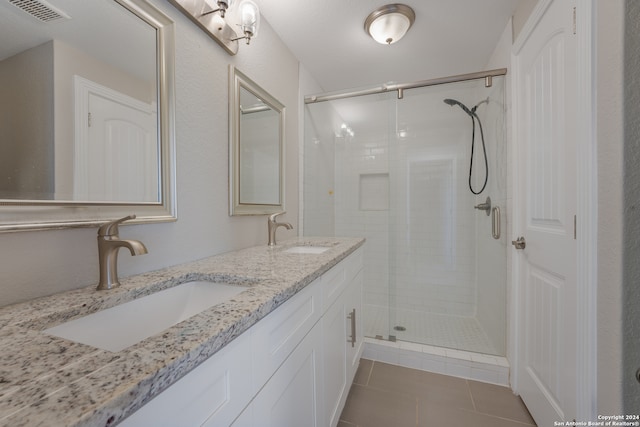 bathroom featuring a shower with shower door, double vanity, and tile patterned flooring