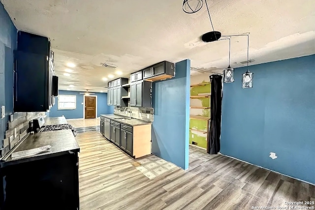 kitchen featuring range, tasteful backsplash, hanging light fixtures, and sink