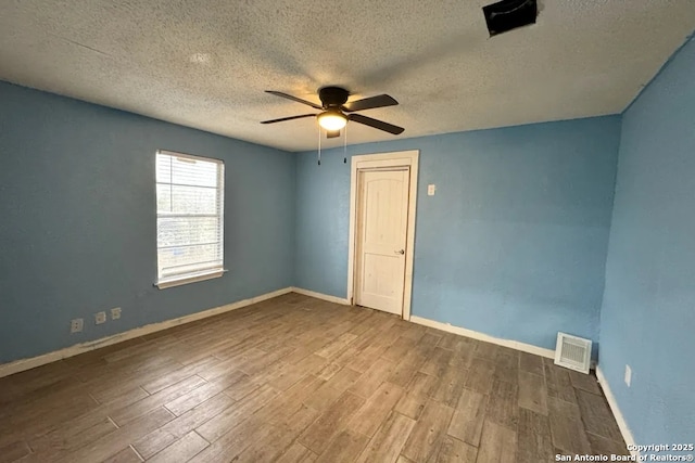 unfurnished room featuring hardwood / wood-style flooring, ceiling fan, and a textured ceiling