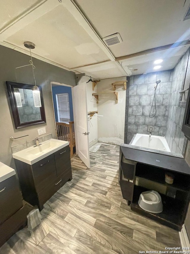 bathroom with ornamental molding, vanity, wood-type flooring, and tiled shower