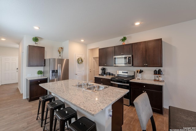 kitchen with sink, a kitchen breakfast bar, a kitchen island with sink, stainless steel appliances, and light hardwood / wood-style flooring