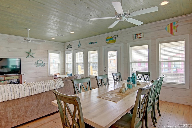 dining area with a healthy amount of sunlight, wood walls, and light hardwood / wood-style floors