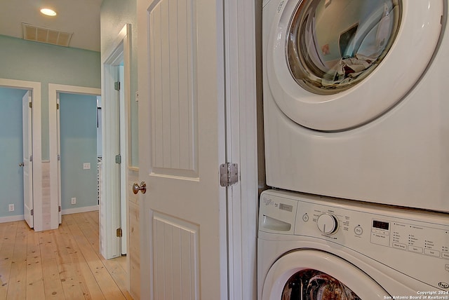 washroom with light hardwood / wood-style floors and stacked washer and dryer