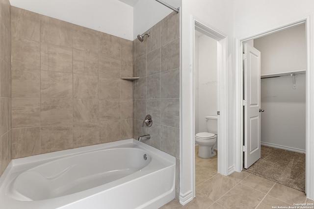 bathroom featuring tiled shower / bath, tile patterned floors, and toilet