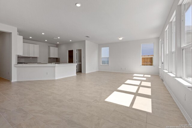 unfurnished living room featuring light tile patterned flooring and a healthy amount of sunlight