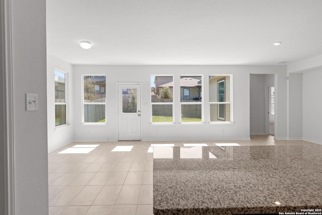 unfurnished living room with light tile patterned floors and a healthy amount of sunlight