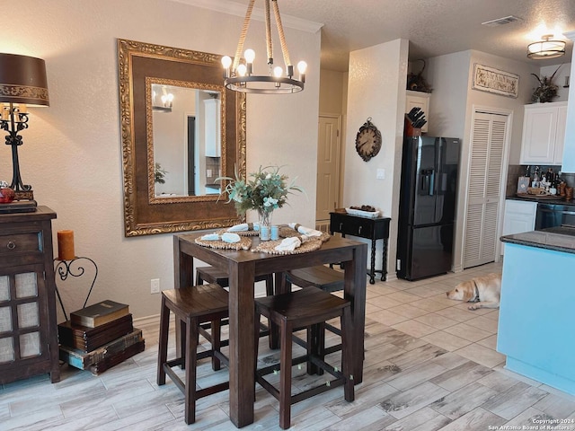 dining room with a textured ceiling, light hardwood / wood-style floors, and an inviting chandelier