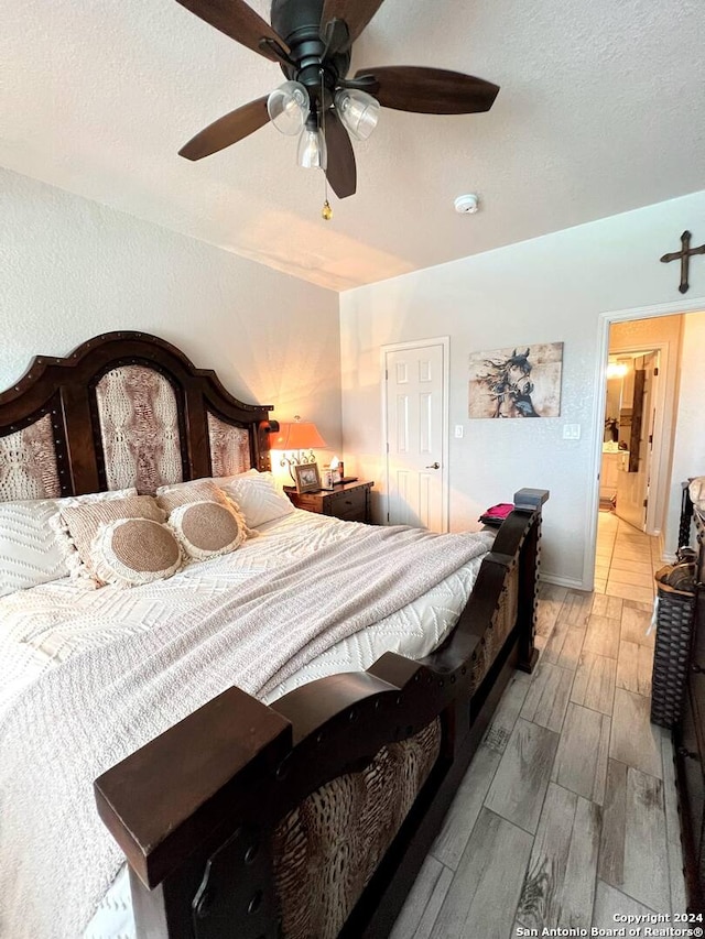 bedroom with a textured ceiling, ceiling fan, and light hardwood / wood-style flooring