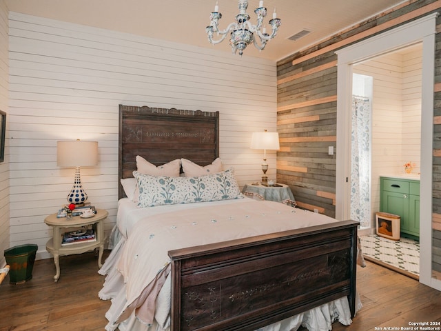 bedroom with wood-type flooring, a chandelier, wooden walls, and visible vents