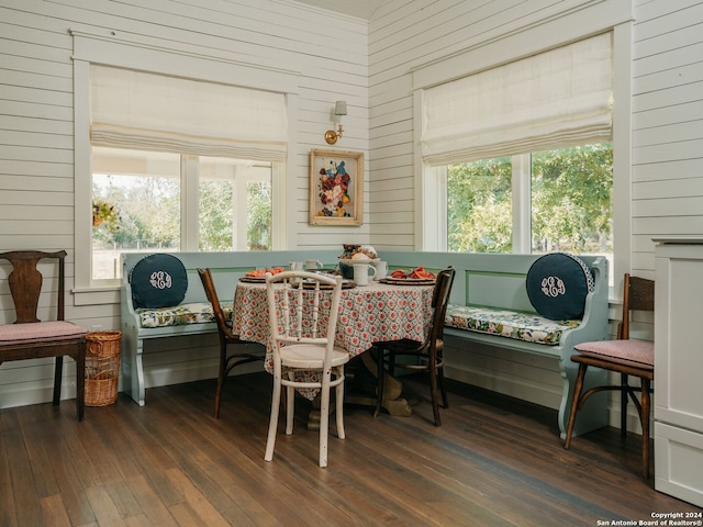 dining area with dark hardwood / wood-style flooring and wooden walls