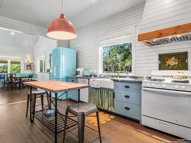 kitchen featuring custom exhaust hood, stainless steel counters, white appliances, a sink, and vaulted ceiling