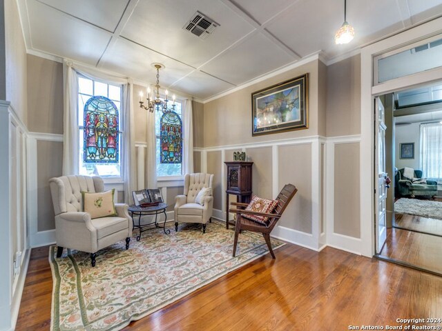 living area with coffered ceiling, hardwood / wood-style floors, a wealth of natural light, and a notable chandelier