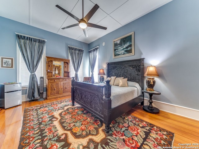 bedroom with ceiling fan, refrigerator, and hardwood / wood-style floors