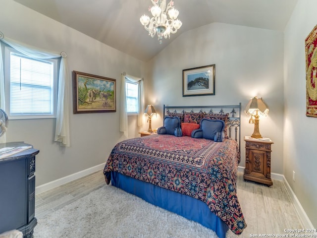 bedroom with a notable chandelier, light wood-type flooring, and lofted ceiling