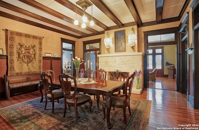 dining room featuring beamed ceiling, a stone fireplace, and dark hardwood / wood-style floors