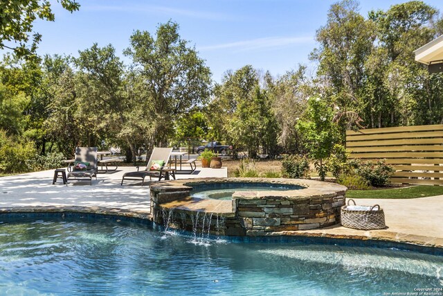 view of pool with a patio area, pool water feature, and an in ground hot tub