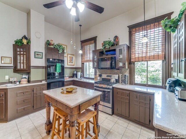 kitchen with light tile patterned floors, a wealth of natural light, black appliances, and hanging light fixtures