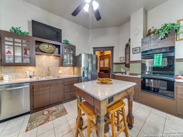 kitchen featuring stainless steel appliances, ceiling fan, sink, light tile patterned flooring, and tasteful backsplash