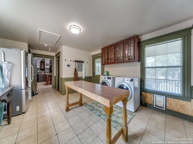 laundry room with cabinets, wooden walls, light tile patterned flooring, and washing machine and clothes dryer