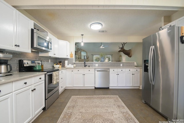 kitchen with sink, pendant lighting, stainless steel appliances, decorative backsplash, and white cabinets