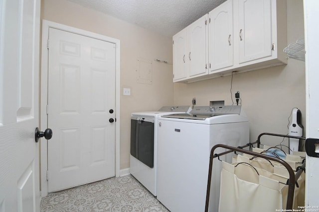 laundry room with light tile patterned floors, washer and clothes dryer, cabinets, and a textured ceiling