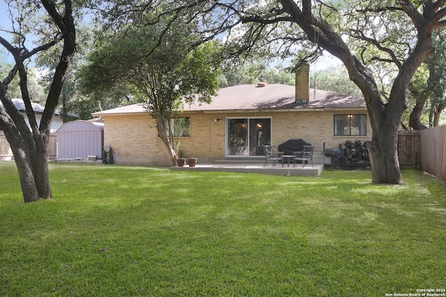 back of property with a yard, a patio, and a storage unit