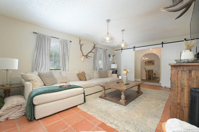 living room with tile patterned floors, a barn door, and a textured ceiling