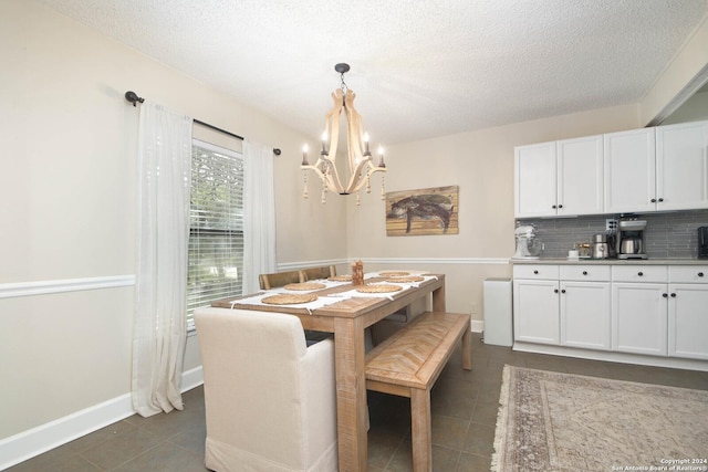 dining room featuring a notable chandelier, a textured ceiling, and dark tile patterned floors