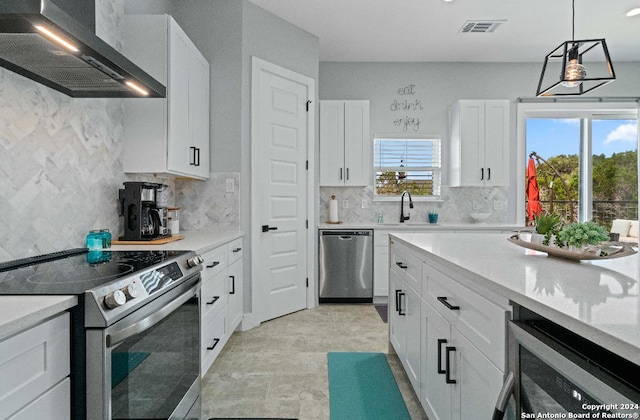 kitchen with white cabinetry, wall chimney range hood, wine cooler, stainless steel appliances, and hanging light fixtures